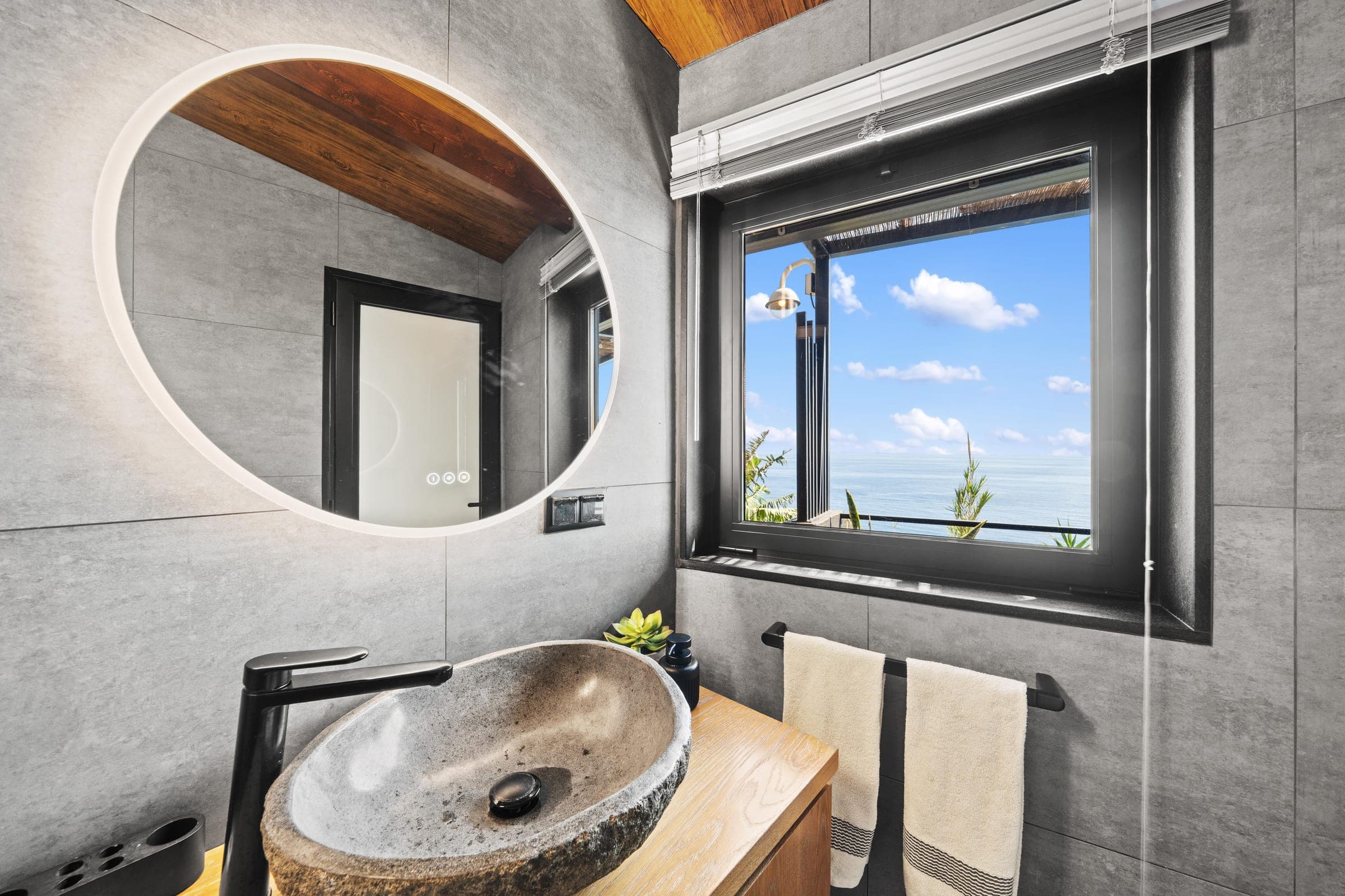 Round mirror, stone basin and a window open to the Atlantic.