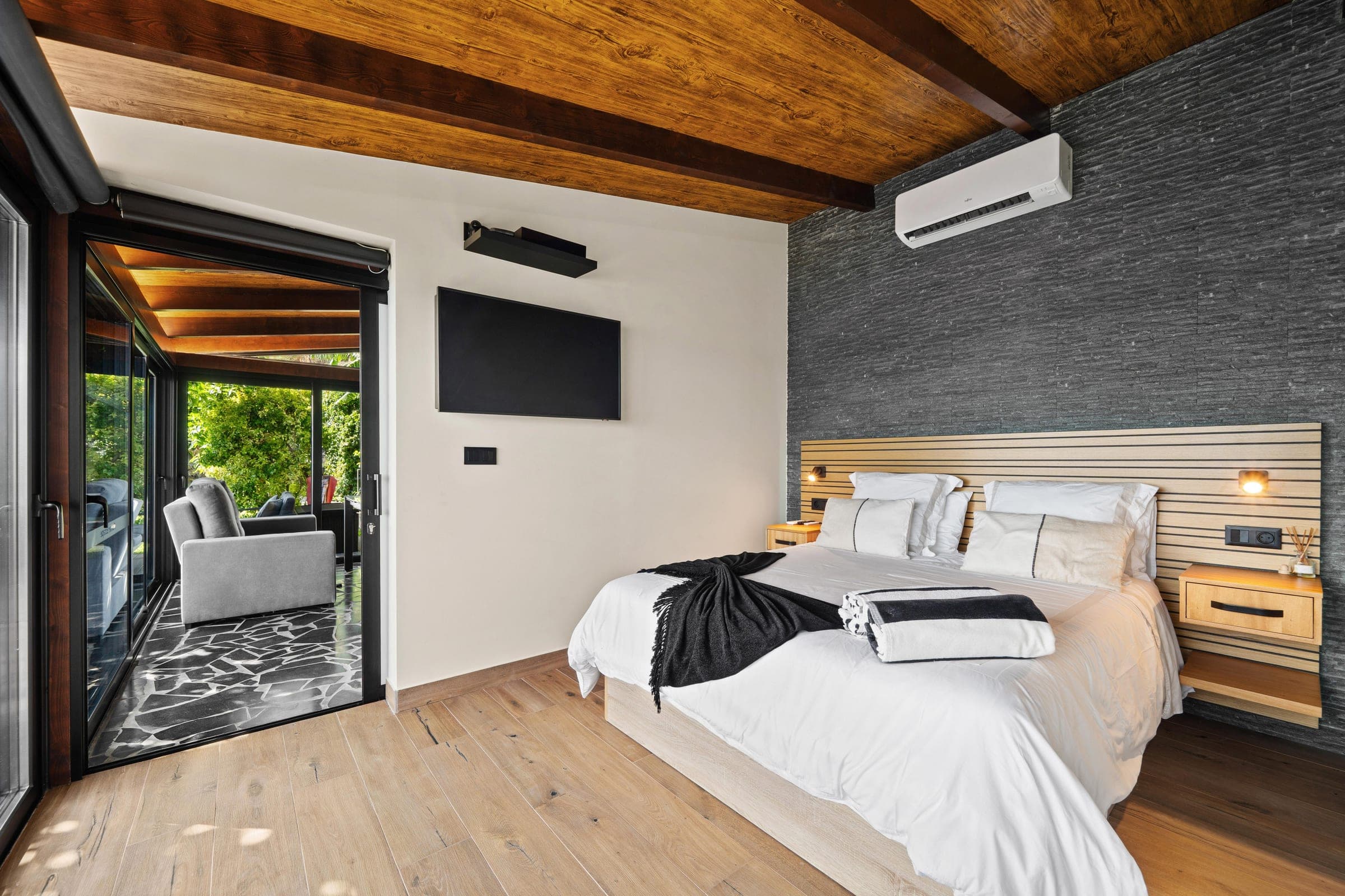 Bedroom opening onto a glassed terrace lounge among the trees.