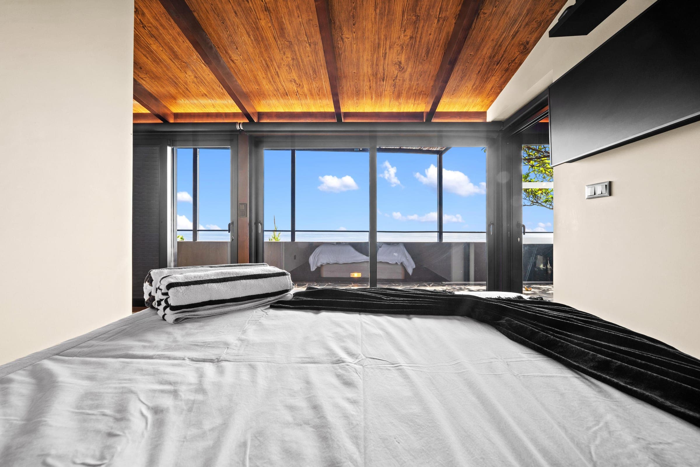 Folded towels on crisp linen, the sea filling the window beyond.