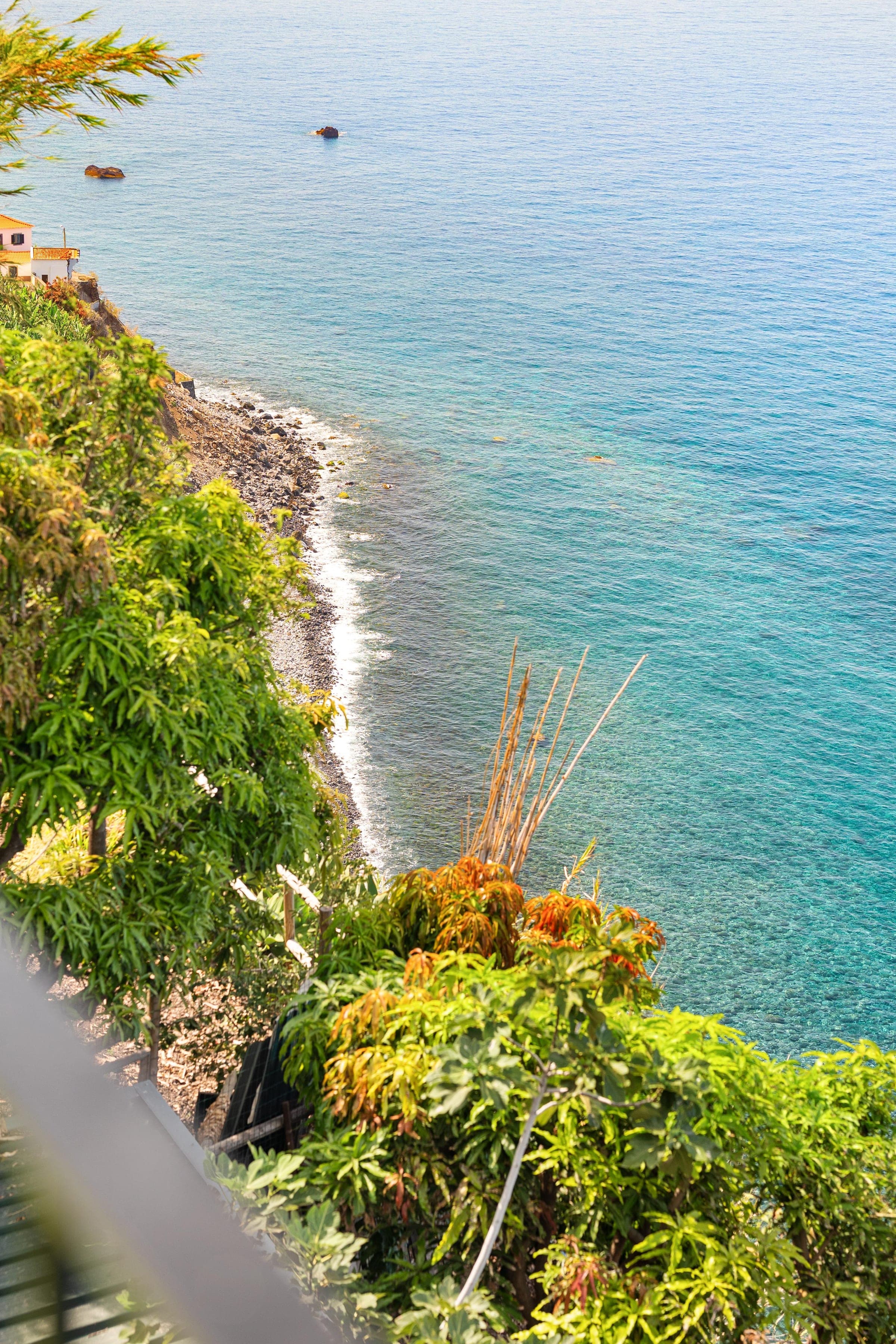 Below the last terrace: the black-pebble shore and the turquoise shallows.