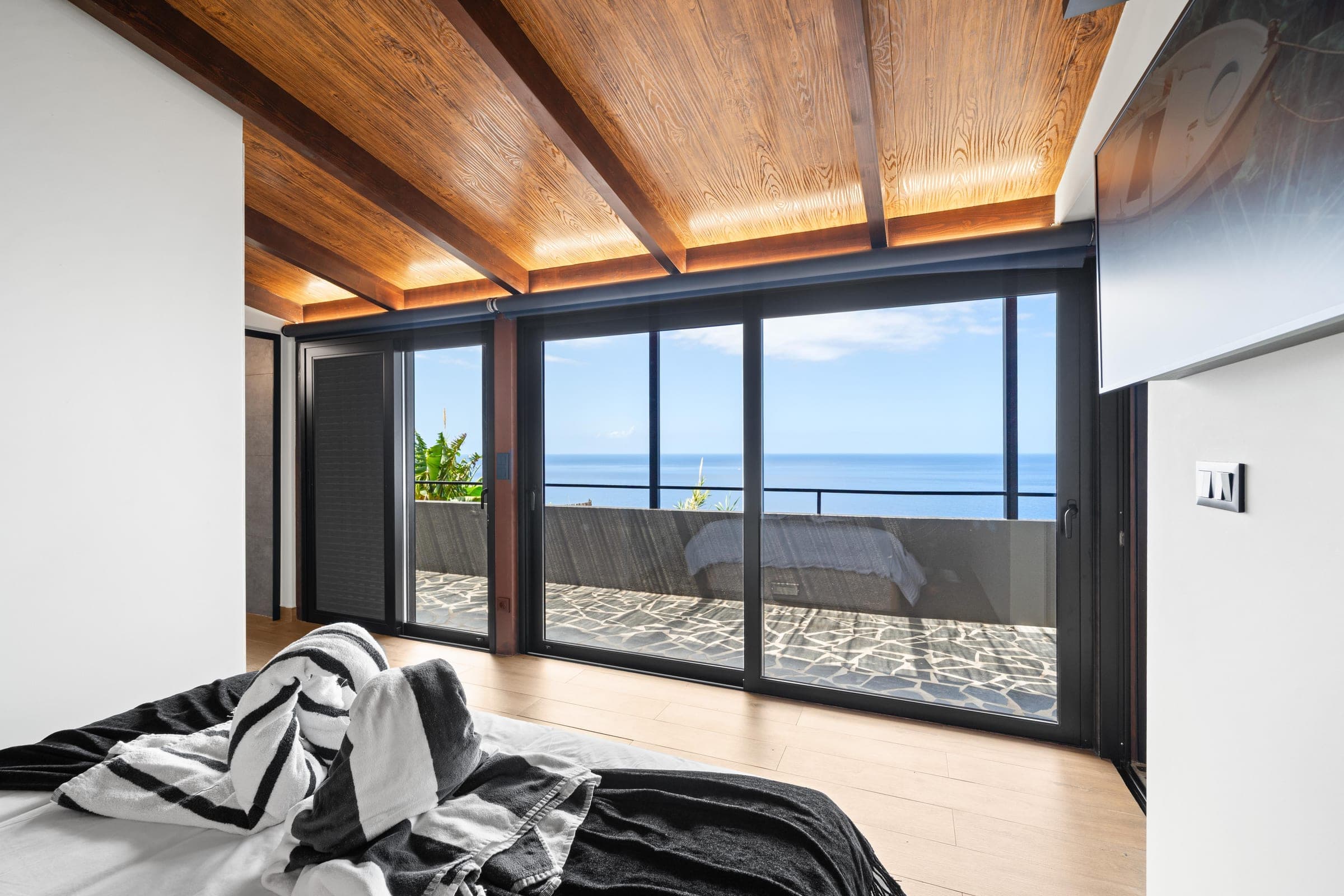 In the bedroom, a wall of sliding glass gives straight onto the terrace and the open sea.