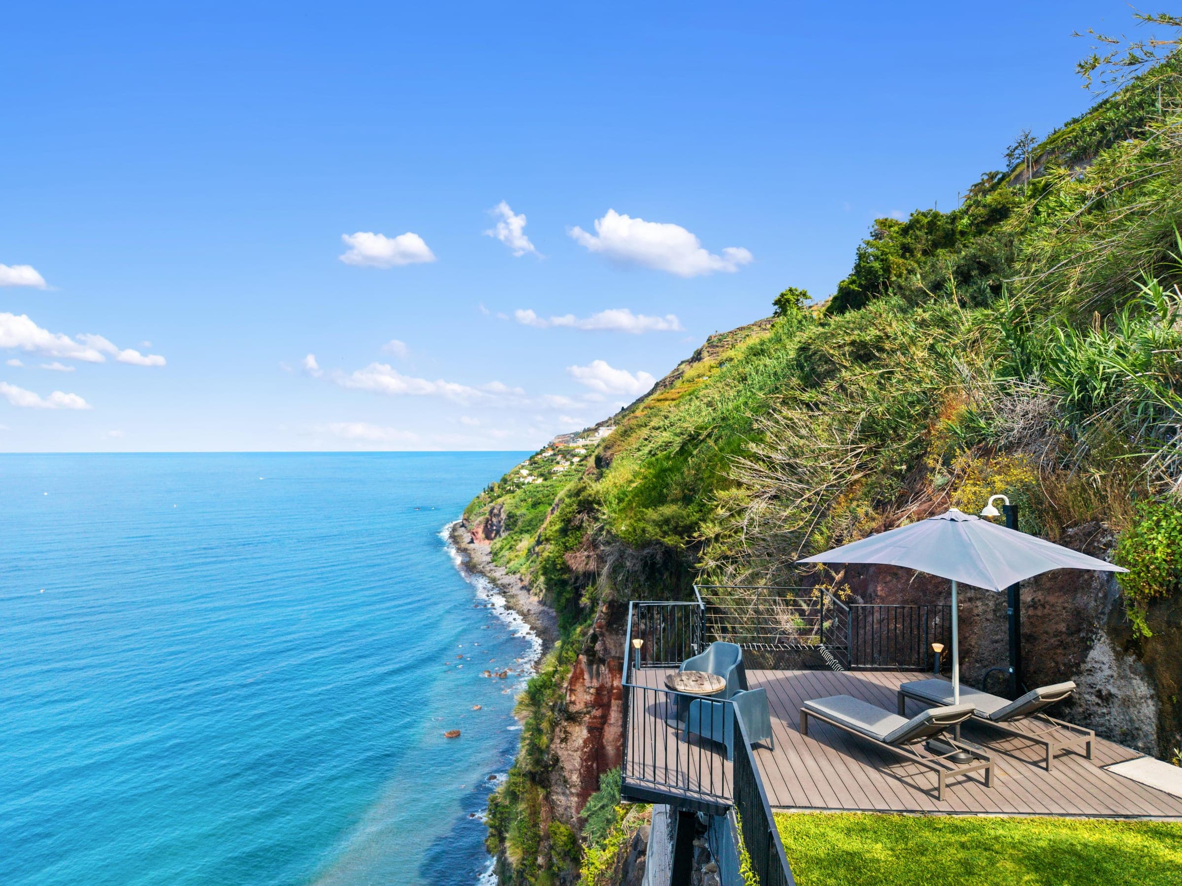 A cliffside deck with loungers cantilevered over the ocean.